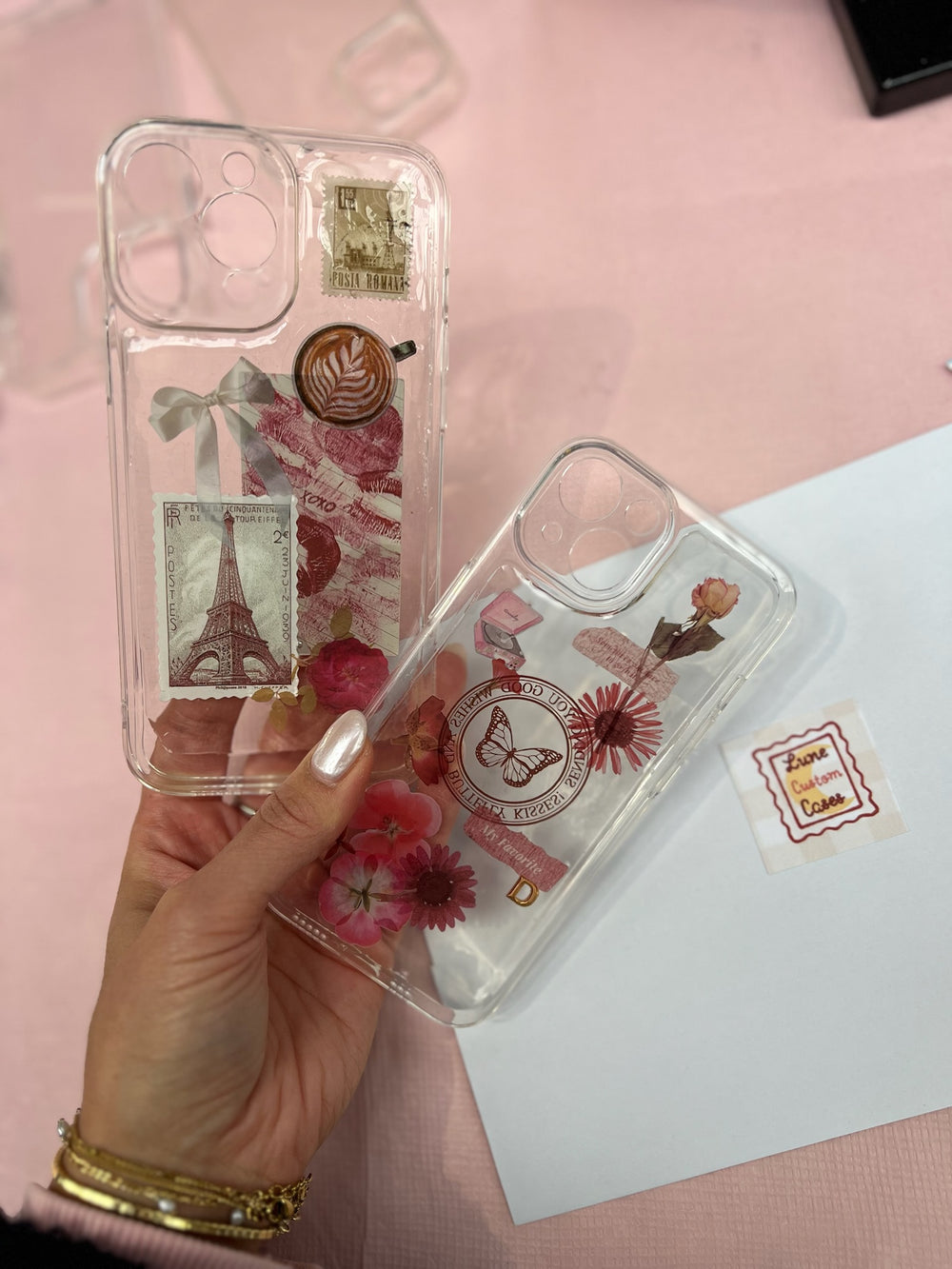 Twee doorzichtige telefoonhoesjes met postzegels en bloemen in een hand