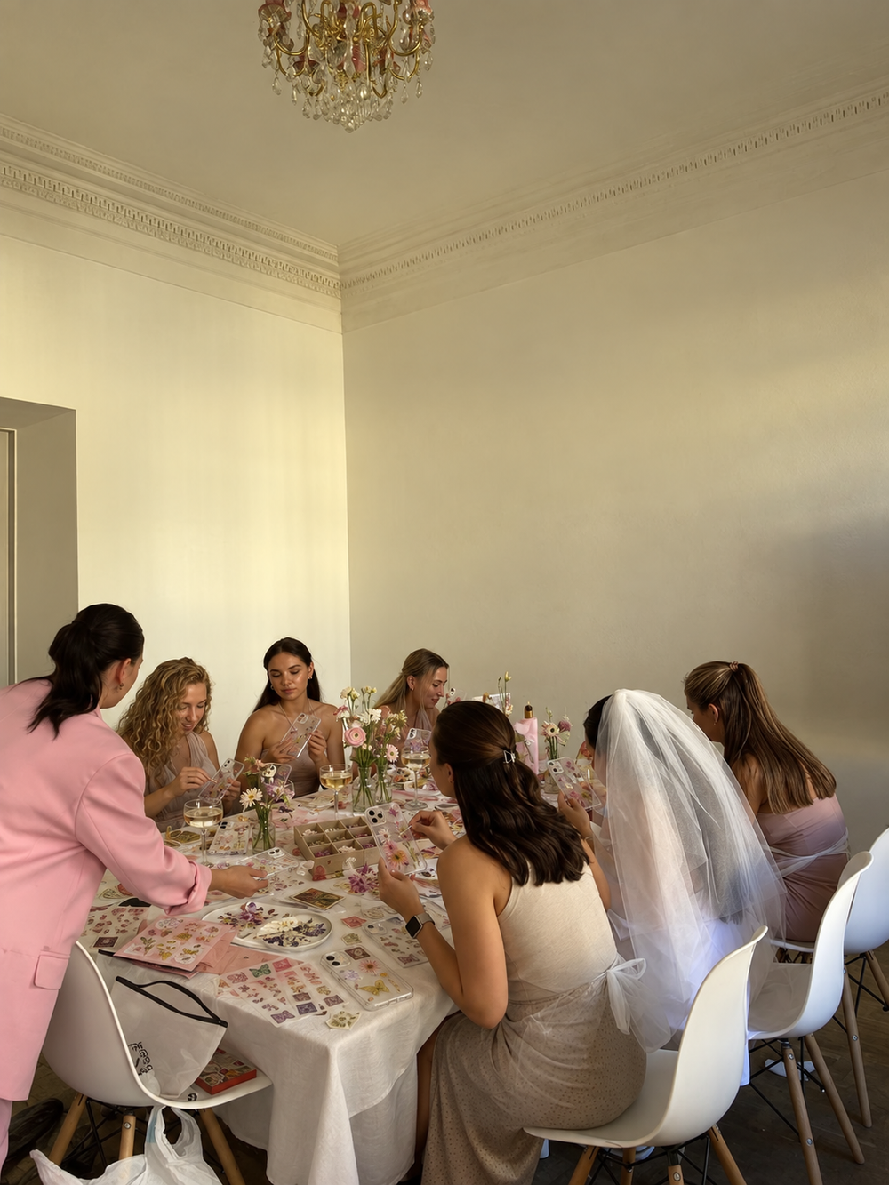 Vrijgezellenfeest met een hoesjesworkshop; de bruid met sluier zit aan tafel