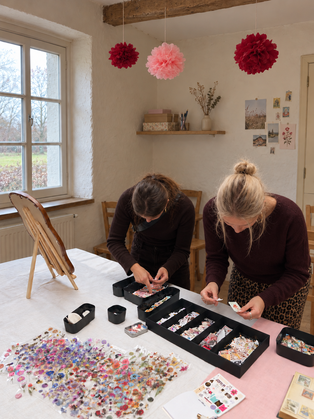 Twee deelnemers ontwerpen een telefoonhoesje aan een tafel vol stickers en postzegels tijdens een Lune-workshop
